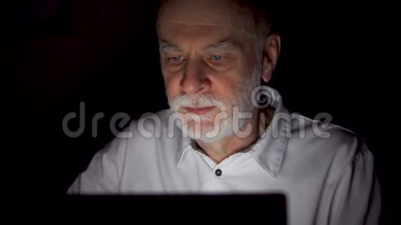 老人在家休息深夜用笔记本电脑阅读新闻只有一张漆黑的脸视频的预览图