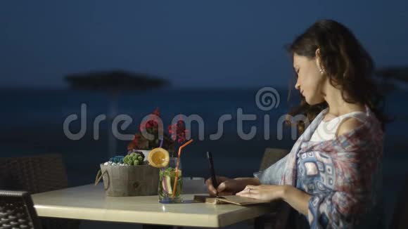 快乐的年轻女子在日记中写下浪漫的回忆在海边放松视频的预览图