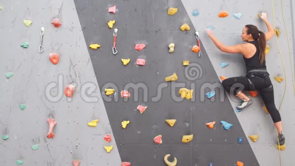 漂亮年轻的运动女孩爬在室内攀岩墙上视频的预览图