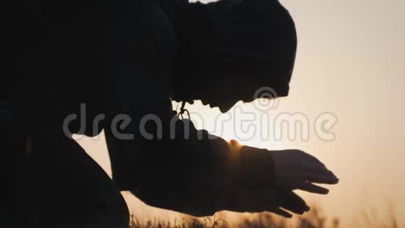 剪影的年轻人在美丽的夕阳下在外面祈祷男性寻求帮助在信仰概念宗教中找到慰藉视频的预览图