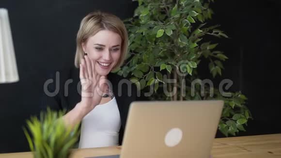 优雅的年轻积极的漂亮女孩坐在咖啡馆里用笔记本电脑视频的预览图