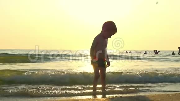 孩子站在海边的水中在海浪中在一个减速的背景下视频的预览图
