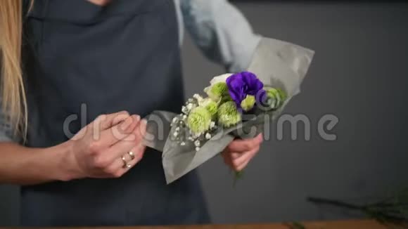 女花店手在装饰纸上包一束花的特写镜头慢镜头视频的预览图