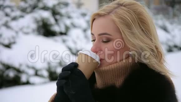 穿着毛皮外套的女孩在冬季公园里喝咖啡视频的预览图