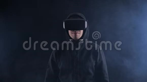 未来派男子戴着VR耳机未来派男子使用虚拟现实眼镜在一个黑暗的烟雾房间视频的预览图