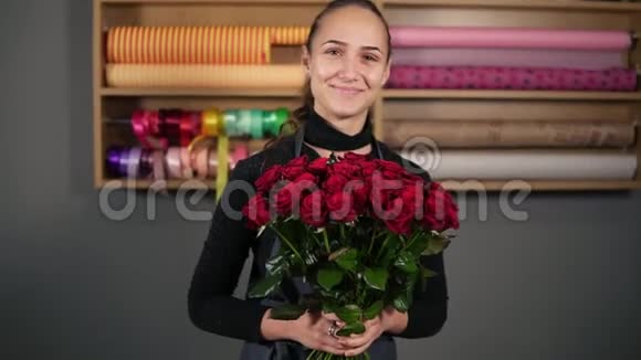 来自专业花店的完美红玫瑰花束年轻迷人的女性花店捧着一束美丽的玫瑰视频的预览图
