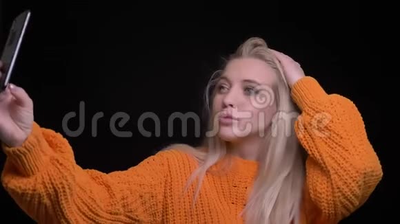 年轻漂亮的白种人女性在手机上自拍的特写镜头背景与黑色隔离视频的预览图