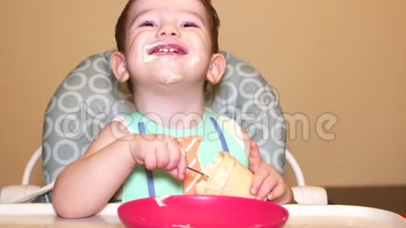 小宝宝坐在高椅后面在胸牌里杯子里放着冰淇淋孩子微笑着视频的预览图