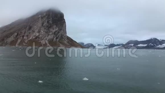 冰在北冰洋移动的背景下海岸上的雾山和山顶视频的预览图