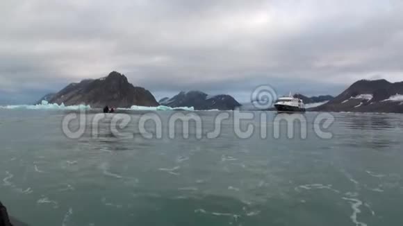 在北极雪山的背景下人们乘船和大型游艇航行视频的预览图