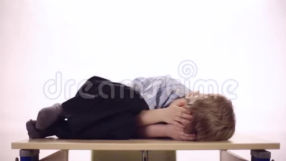 有趣的男孩躺在学校桌子上视频的预览图