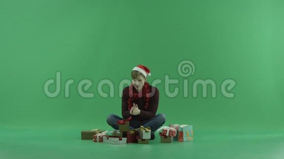男人打开空礼物盒坐在圣诞礼物中间绿色彩色钥匙背景视频的预览图