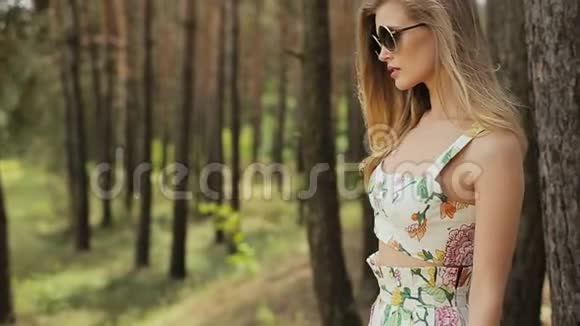 时尚模特戴着太阳镜对着森林附近的摄像机摆姿势视频的预览图