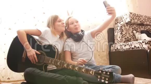 两个女青少年在家里坐在地板上自拍和摆手乐器视频的预览图