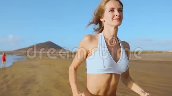 一位身材苗条的年轻女子在日出时在海上从事体操她沿着海岸跑步视频的预览图