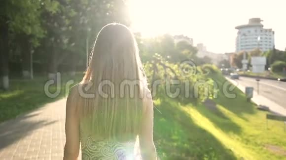 日落时分一个迷人的金发女人走在人行道上视频的预览图