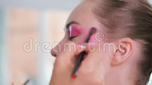 眼妆师应用和羽毛眼影粉漂亮的女人模特脸特写镜头视频的预览图