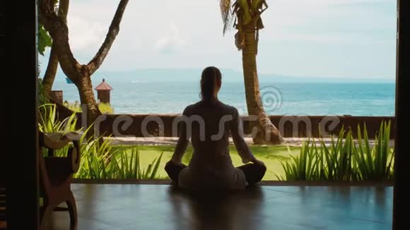 女人的剪影正在海洋海滩上的莲花位置练习瑜伽冥想美丽的景色自然的声音视频的预览图
