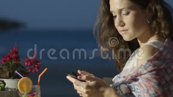 在户外餐厅的智能手机上在线聊天的快乐美女视频的预览图