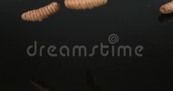 姜黄姜黄落在黑背景下的根印度香料慢运动视频的预览图