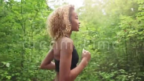 年轻美丽的非裔美国女人卷发在森林里奔跑靠近视频的预览图