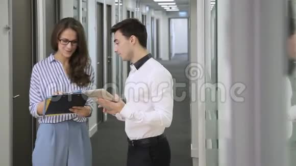在走廊办公室男人带着平板电脑女人带着文件验证数据视频的预览图