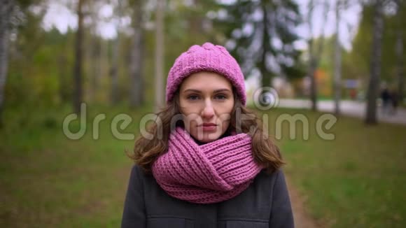 夏日公园美丽的年轻悲伤女人的肖像特写的脸戴着针织帽子和围巾的漂亮年轻女人视频的预览图