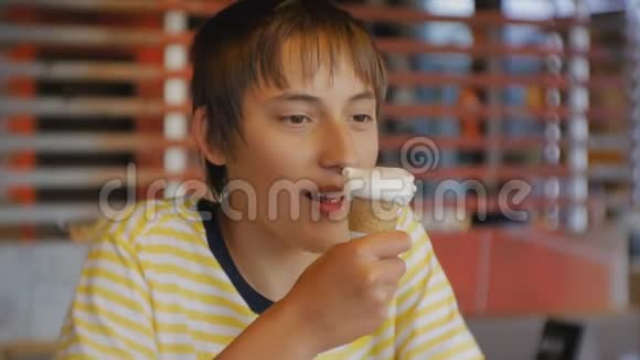 青少年吃快餐在快餐店吃冰淇淋锥的青少年男孩的肖像视频的预览图