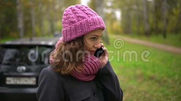 年轻的美女在秋天的公园里散步时她用手机拍着黄红叶的背景视频的预览图