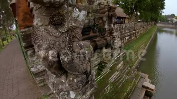 在巴厘岛塔曼阿云王府入口处的石像手持照相机拍摄视频的预览图