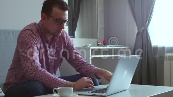 年轻人坐在桌边喝咖啡在电脑上和一个朋友视频通话视频的预览图
