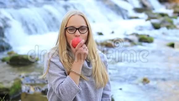 在瀑布附近吃苹果的女孩视频的预览图