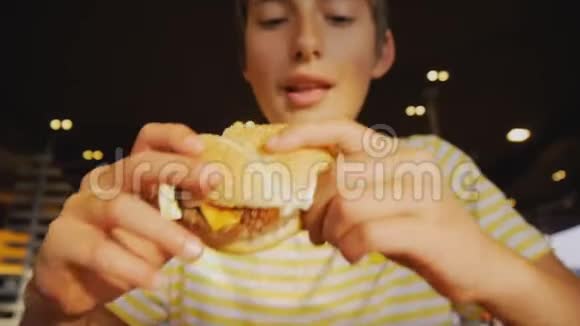 青少年吃快餐快餐厅里少年咬芝士汉堡的特写镜头视频的预览图