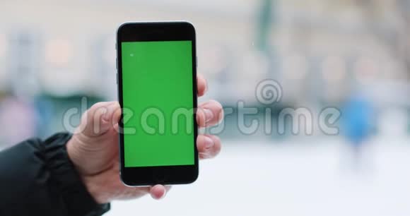雪落在一个男人身上他手里拿着智能手机手里拿着绿色的屏幕视频的预览图