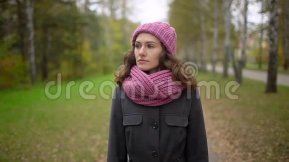 女人享受秋日她在公园里散步周围有五颜六色的叶子动作缓慢视频的预览图
