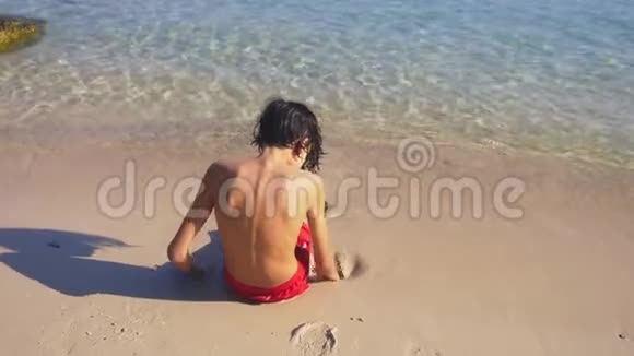 在热带海滩上建造沙堡的少年视频的预览图