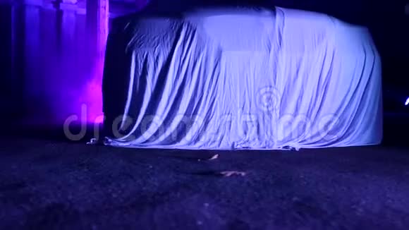 站在废弃房子里的烟雾中被布料覆盖的汽车用紫色照明视频的预览图