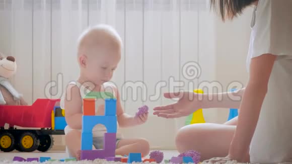 妈妈和她的孩子在室内玩玩具在家里在地板上爬行有趣的小男孩妈妈和小儿子一起玩视频的预览图