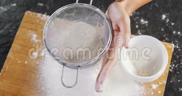 女人从木板上的碗里筛面粉视频的预览图