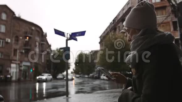小镇上一个下雨天晚上一个年轻的女人在街上用手机视频的预览图