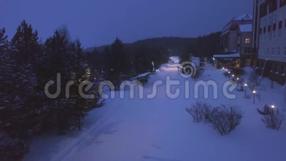 冬季森林中酒店的俯视图剪辑晚上沿着旅馆铺着白雪的小路视频的预览图