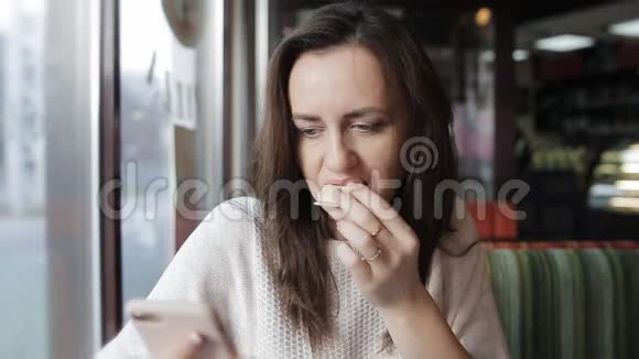 一个女人在咖啡馆里吃披萨用手机社交和电子邮件晚餐和网页浏览视频的预览图