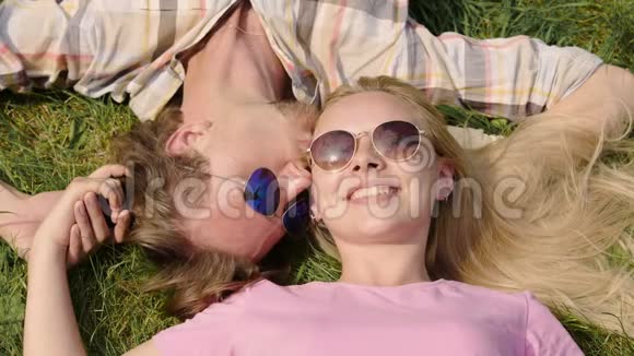 年轻夫妇躺在草地上牵着手男朋友亲吻女朋友约会视频的预览图