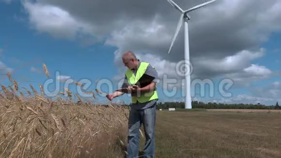 农民在风力涡轮机附近检查谷物视频的预览图