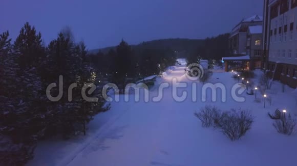 冬季森林中酒店的俯视图剪辑晚上沿着旅馆铺着白雪的小路视频的预览图