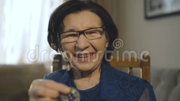 快乐的老妇人展示了一枚银比特币用于相机和微笑视频的预览图