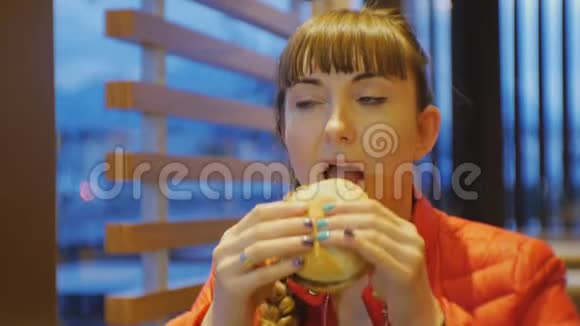 女人吃快餐年轻白种人女性在快餐店咬和咀嚼芝士汉堡的肖像视频的预览图