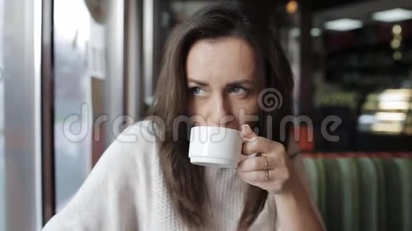 一个女人在咖啡馆喝茶用手机社交和电子邮件晚餐和网页浏览视频的预览图