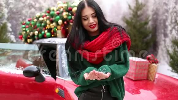 漂亮的女孩正在玩雪附近的红色汽车与装饰圣诞树视频的预览图