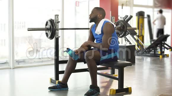 在健身房里坐在训练器材上的美国黑人运动员视频的预览图